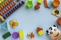 Top view on children`s educational games, frame kids toys on blue paper background. Cubes, circles, cow, ladybug, abacus,