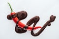 Top view chili with spilled melted dark chocolate on white background. Royalty Free Stock Photo