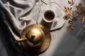 Top view of Chinese, beautiful brass teapot, teacup on gray tray with brown bouquet on tablecloth in sunlight