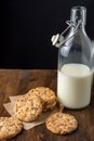 Top view of chocolate chip cookies on brown paper and dark wooden table with bottle of milk, black background Royalty Free Stock Photo