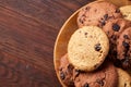 Top view of chocolate chip cookies on a wooden plate over rustic background, selective focus Royalty Free Stock Photo