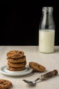 Top view of chocolate cookies on white plate, spoon and bottle with milk, on white table Royalty Free Stock Photo