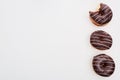 Top view of chocolate tasty whole doughnuts near bitten one on white background with copy space.
