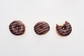 Top view of chocolate tasty whole doughnuts near bitten one on white background.