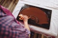Top view of chocolatier holding cake scraber and cooling melted chocolate mass on a marble table