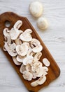 Top view, chopped mushrooms on wooden cutting board over white wooden background. Flat lay, overhead, from above Royalty Free Stock Photo