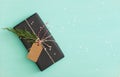 Top view on Christmas or birthday gift wrapped in black paper and decorated with craft tag, twine and tree brunch Royalty Free Stock Photo