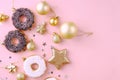 Top view of christmas composition decoration of snowflakes, stars, balls, donuts of golden and white color on a pink background.