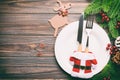 Top view of Christmas dinner on wooden background. Plate, utensil, fir tree and holiday decorations with copy space. New Year time Royalty Free Stock Photo