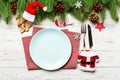 Top view of Christmas dinner on wooden background. Plate, utensil, fir tree and holiday decorations with copy space. New Year time Royalty Free Stock Photo