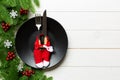 Top view of Christmas dinner on wooden background. Plate, utensil, fir tree and holiday decorations with copy space. New Year time Royalty Free Stock Photo