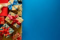 Top view on Christmas gifts wrapped in gift paper decorated with ribbon on blue paper background. Royalty Free Stock Photo