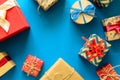 Top view on Christmas gifts wrapped in gift paper decorated with ribbon on blue paper background. Royalty Free Stock Photo