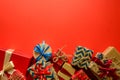 Top view on Christmas gifts wrapped in gift paper decorated with ribbon on red paper background.
