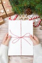 Top view of christmas letter in hand. Close up of hands holding empty wishlist on wooden table with xmas decoration Royalty Free Stock Photo