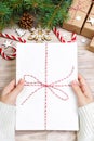 Top view of christmas letter in hand. Close up of hands holding empty wishlist on wooden table with xmas decoration Royalty Free Stock Photo