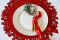 Christmas Table Place Setting with cutlery, branch of Christmas tree and red ribbon on red woolen and white background. New Year Royalty Free Stock Photo