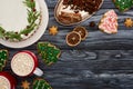 Top view of christmas pie, two cups of cocoa with marshmallows, spices and christmas tree cookies on dark wooden table.