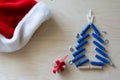 Christmas tree shape with dowels, nuts, screws and gift on a plywood background, Santa`a hat. Cope space, top view