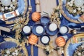 Top view Christmastime table setting, festive dinnerware decorated with details and candles in Blue and Gold colors. Navy Blue