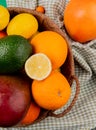 top view of citrus fruits as mango orange avocado lemon in basket on plaid cloth background Royalty Free Stock Photo