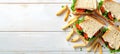 Top view of classic sandwich and fries on wooden table with space for text placement