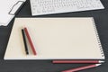 Top view of clean spiral notepad on dark wooden desktop with keyboard and pencils. Drawing, workplace, supplies and art concept. Royalty Free Stock Photo