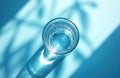Top view of clear water glass with ripples inside on blue surface. Sunlight casts abstract shadow shapes creating bright light Royalty Free Stock Photo