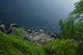 Top view from the cliff to the calm water of the lake on a summer day. Stones and rock are visible in shallow water Royalty Free Stock Photo