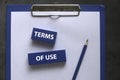 Top view of clipboard with paper,pencil and blue wooden cube written with Terms Of Use on grey background Royalty Free Stock Photo