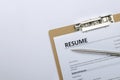 Top view of clipboard and resume form on it, silver pen on the white surface.Empty space