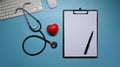 Clipboard, stethoscope and red heart on blue background. Healthcare and medical concept. Royalty Free Stock Photo