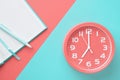 Top view clock and notepad with a pencil on a colored background