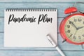 Top view of clock, pen and notebook written with PANDEMIC PLAN Royalty Free Stock Photo