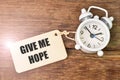 Top view of clock and wooden board written with GIVE ME HOPE Royalty Free Stock Photo