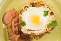 over light egg in a potato nest with crisp bacon and parsley