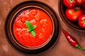 Top view close-up of bowl of gazpacho soup and bowl of fresh tomatoes on brown background Royalty Free Stock Photo