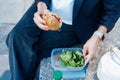Top view close up business woman eating sandwich and fresh salad on lunch break sitting on bench at park. Balanced diet Royalty Free Stock Photo