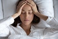 Top view depressed woman suffering from headache, lying in bed