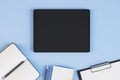 Top view and close up of empty black tablet on blue desktop with supplies. Work place and stationery objects concept. Mock up, 3D