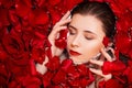 Top view, close-up face of a young woman in a bathtub full of red rose petals. Beauty portrait of an attractive girl. Royalty Free Stock Photo