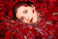 Top view, close-up face of a young woman in a bathtub full of red rose petals. Beauty portrait of an attractive girl. Royalty Free Stock Photo