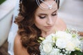 Top view of a close-up of a Greek bride admiring her white bouquet of roses, lowered her eyes down, showing her thick