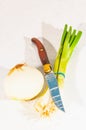 Half a yellow onion, four scalions and knife with serated blade Royalty Free Stock Photo