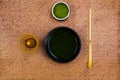 Top view and close up of isolated set for brewing green Matcha tea: one bamboo whisk and scoop, ceramic bowl on terracotta stone Royalty Free Stock Photo