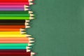 Top view, close up of many, bright multi colored wooden pencils in a row on a dark green background with copy space Royalty Free Stock Photo