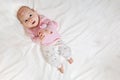 Top view and close-up portrait of cute adorable baby girl wearing pink body in bedroom. Imagining. Newborn child relaxing smiling, Royalty Free Stock Photo