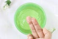 Top view of close up woman finger applying aloe vera gel cream in green container Royalty Free Stock Photo
