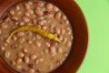 Top view closeup of a bean porridge topped with yellow cayenne in a brown bowl