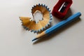 Top view closeup of a blue pencil with the shaving and the red sharpener on a white background Royalty Free Stock Photo